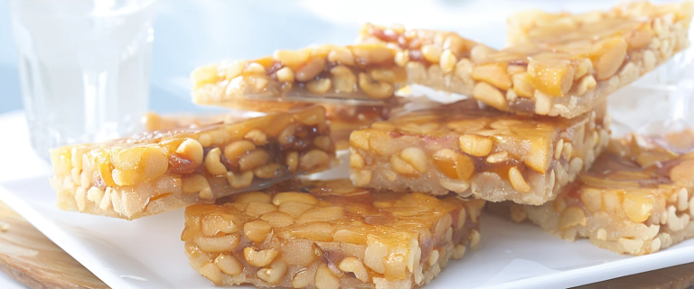 Trozos de pé-de-moleque, dulce brasileño de maní y azúcar, con textura crujiente y color caramelo.