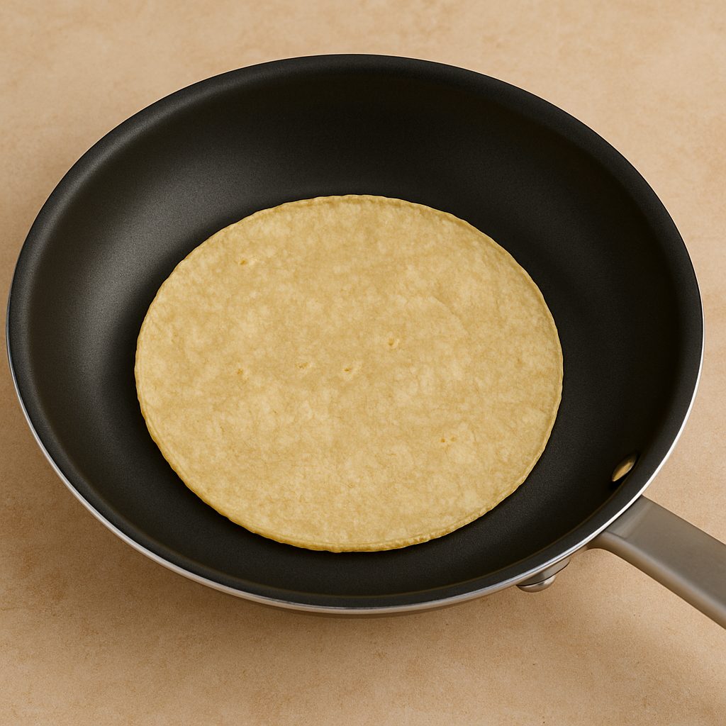 Tortilla de maíz calentándose en una sartén, lista para ser utilizada en la preparación de tacos.